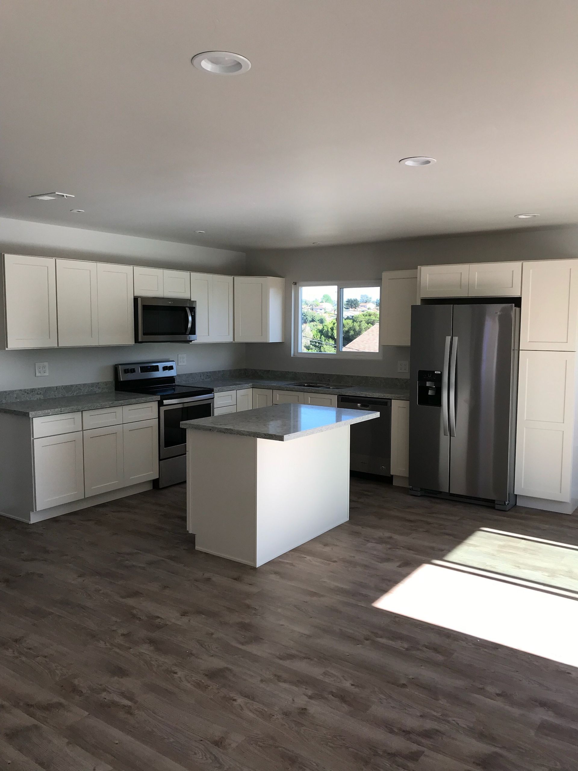 An empty kitchen with stainless steel appliances and white cabinets