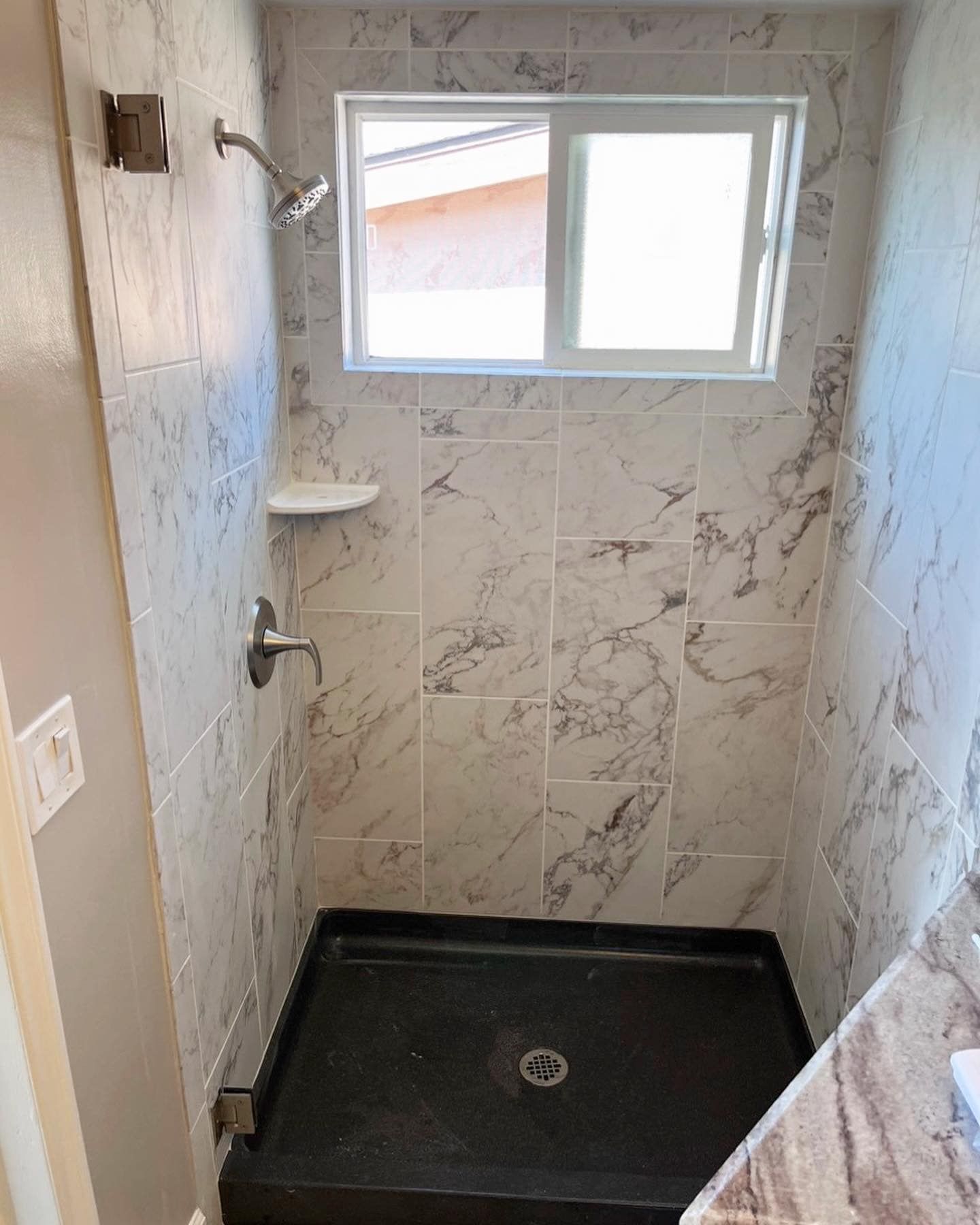 A bathroom with a walk in shower and a window.