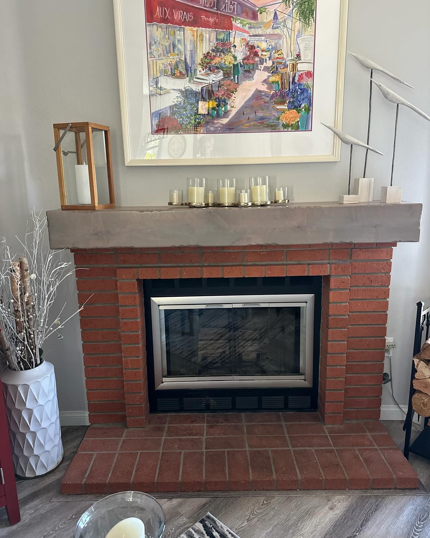 A living room with a brick fireplace and a painting on the wall above it.