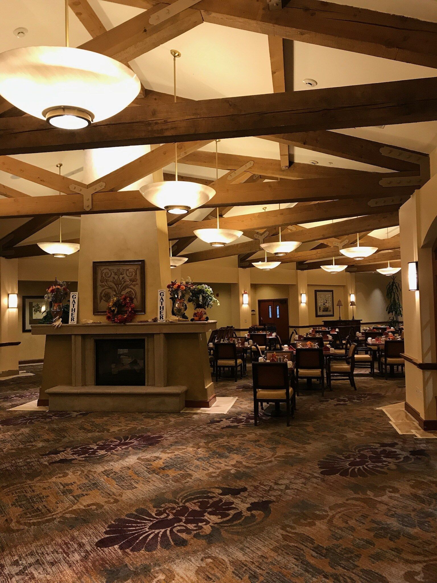 A large dining room with tables and chairs and a fireplace.