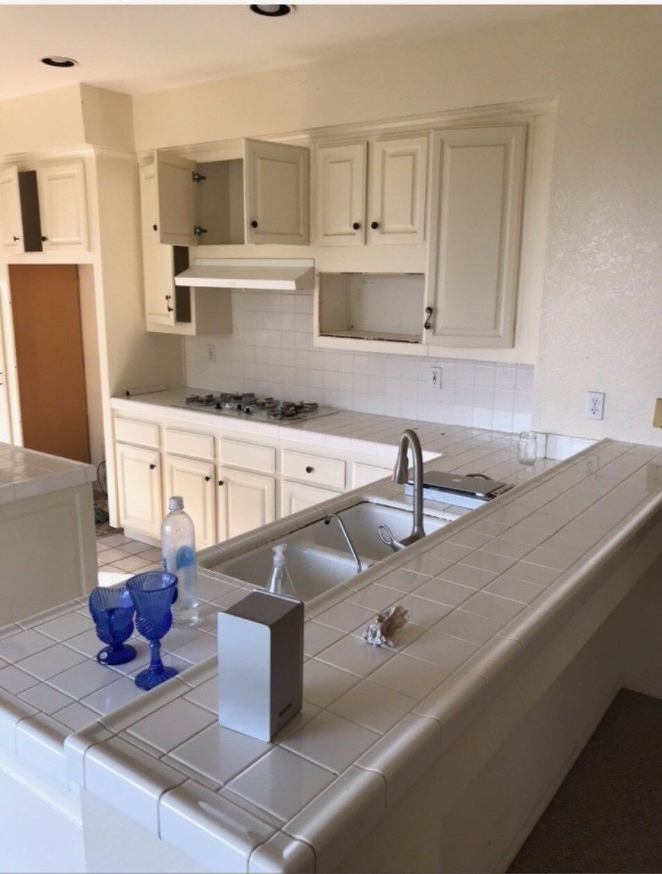 A kitchen with white cabinets and blue glasses on the counter