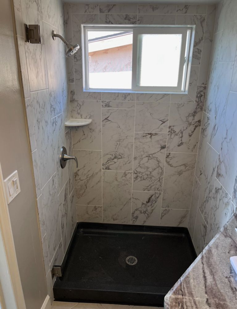 A bathroom with a walk in shower and a window.