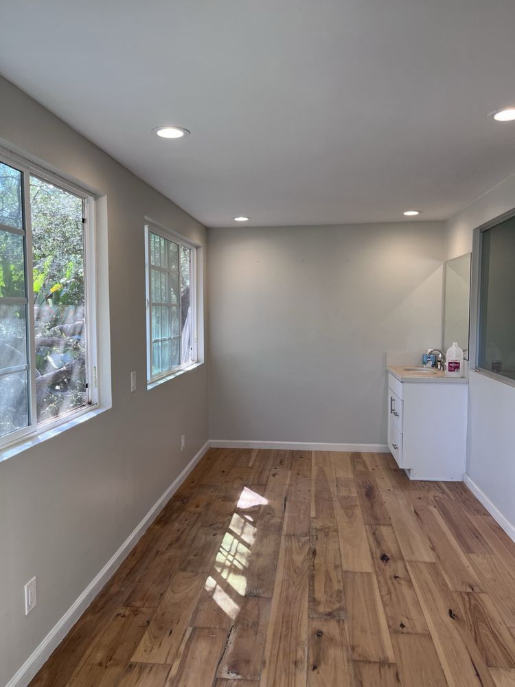 An empty room with hardwood floors and lots of windows.