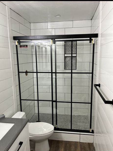 A bathroom with a toilet , sink and shower stall.