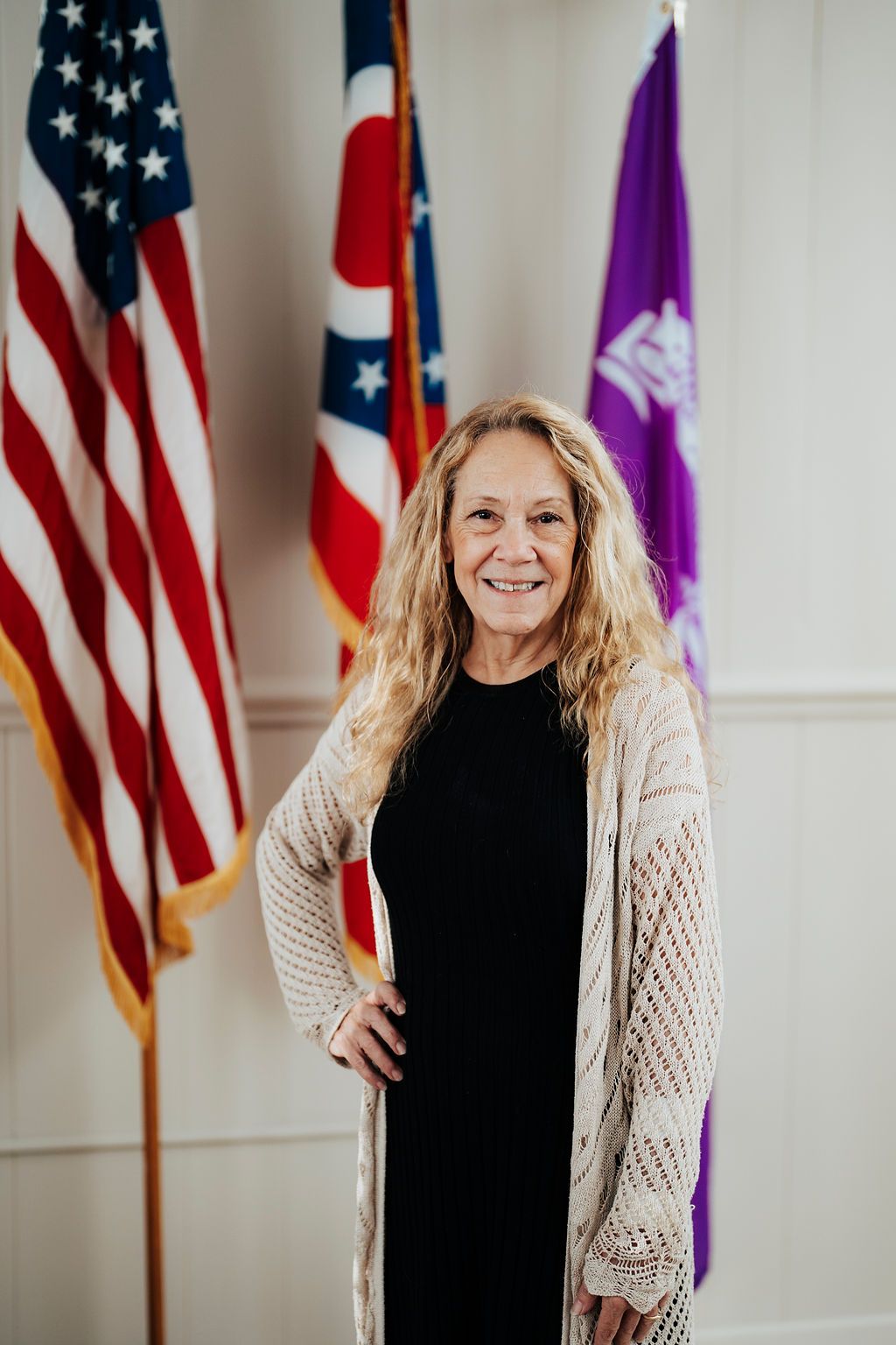 A woman is standing in front of three american flags.