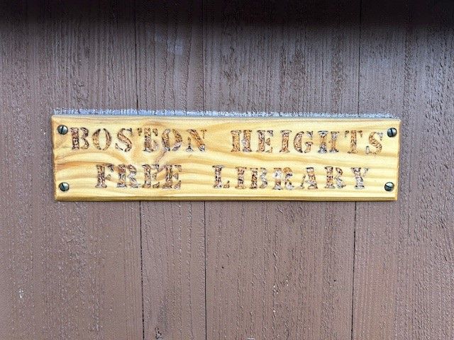 A wooden sign that says boston heights free library