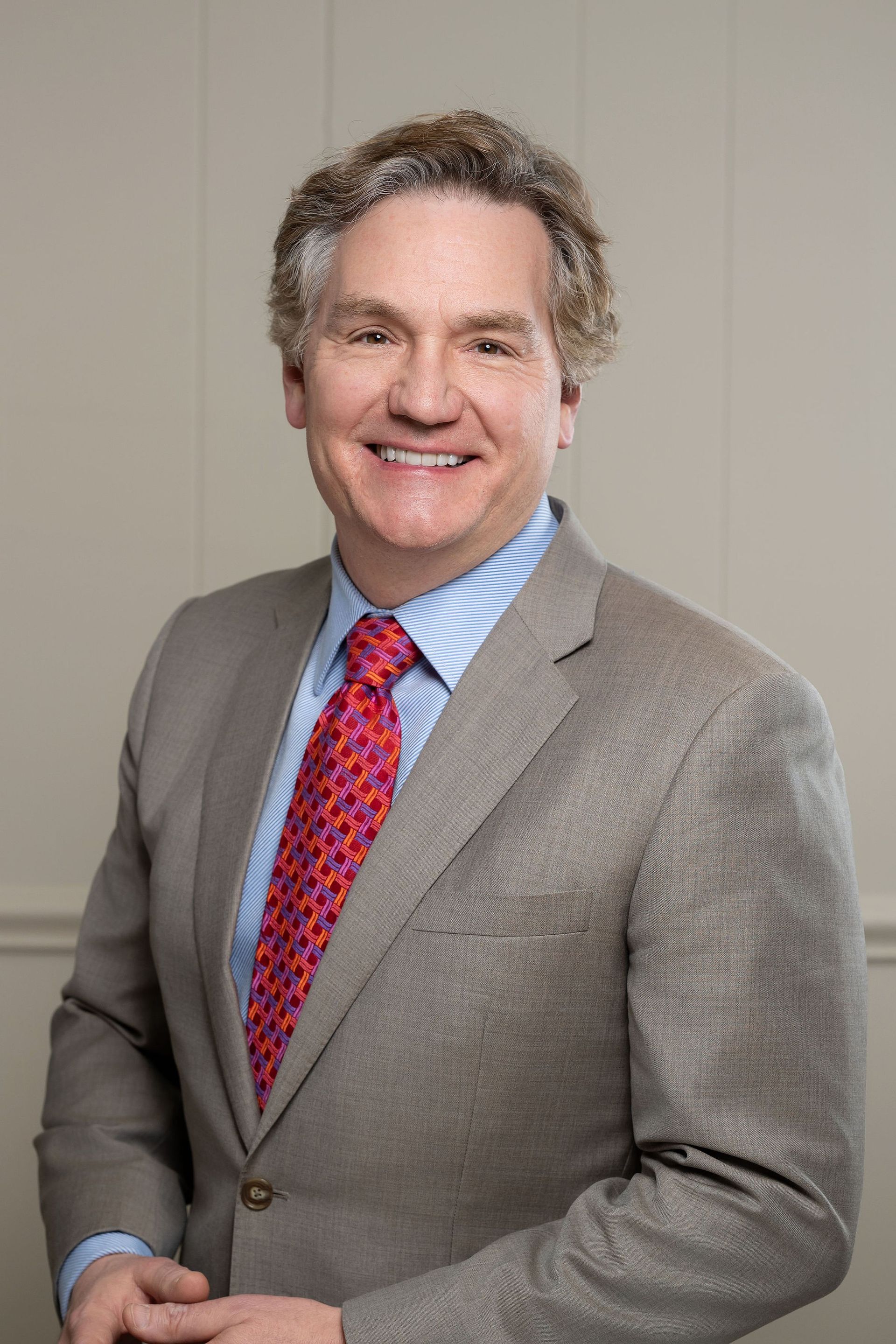 A man in a suit and tie is smiling for the camera