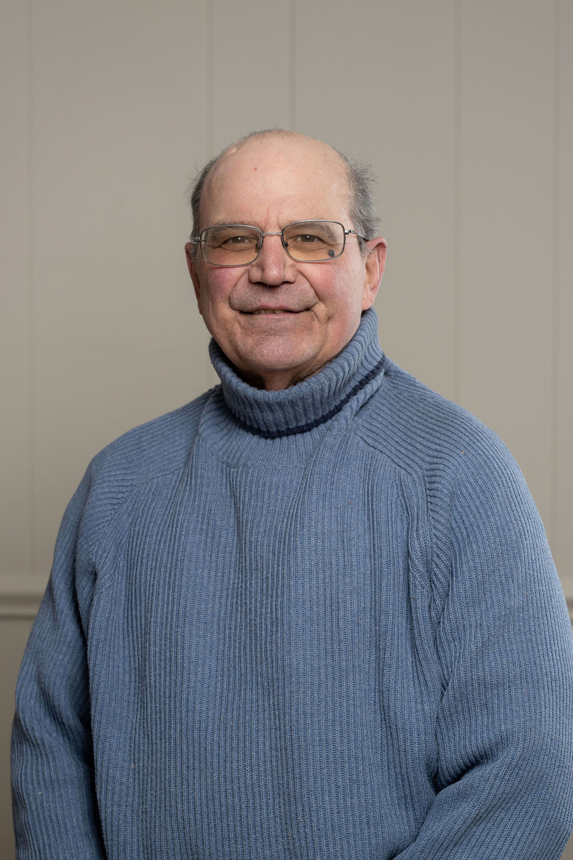 A man in a grey shirt is standing in front of two american flags.