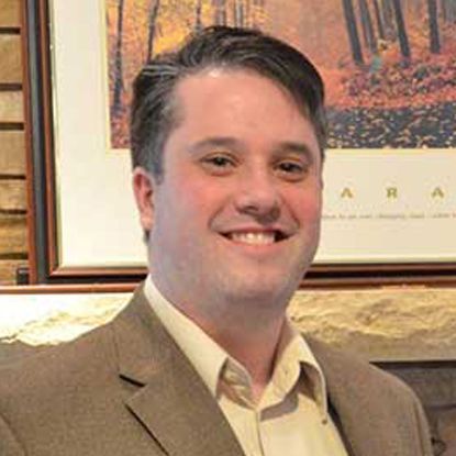 A man in a suit and tie is smiling in front of a framed picture.