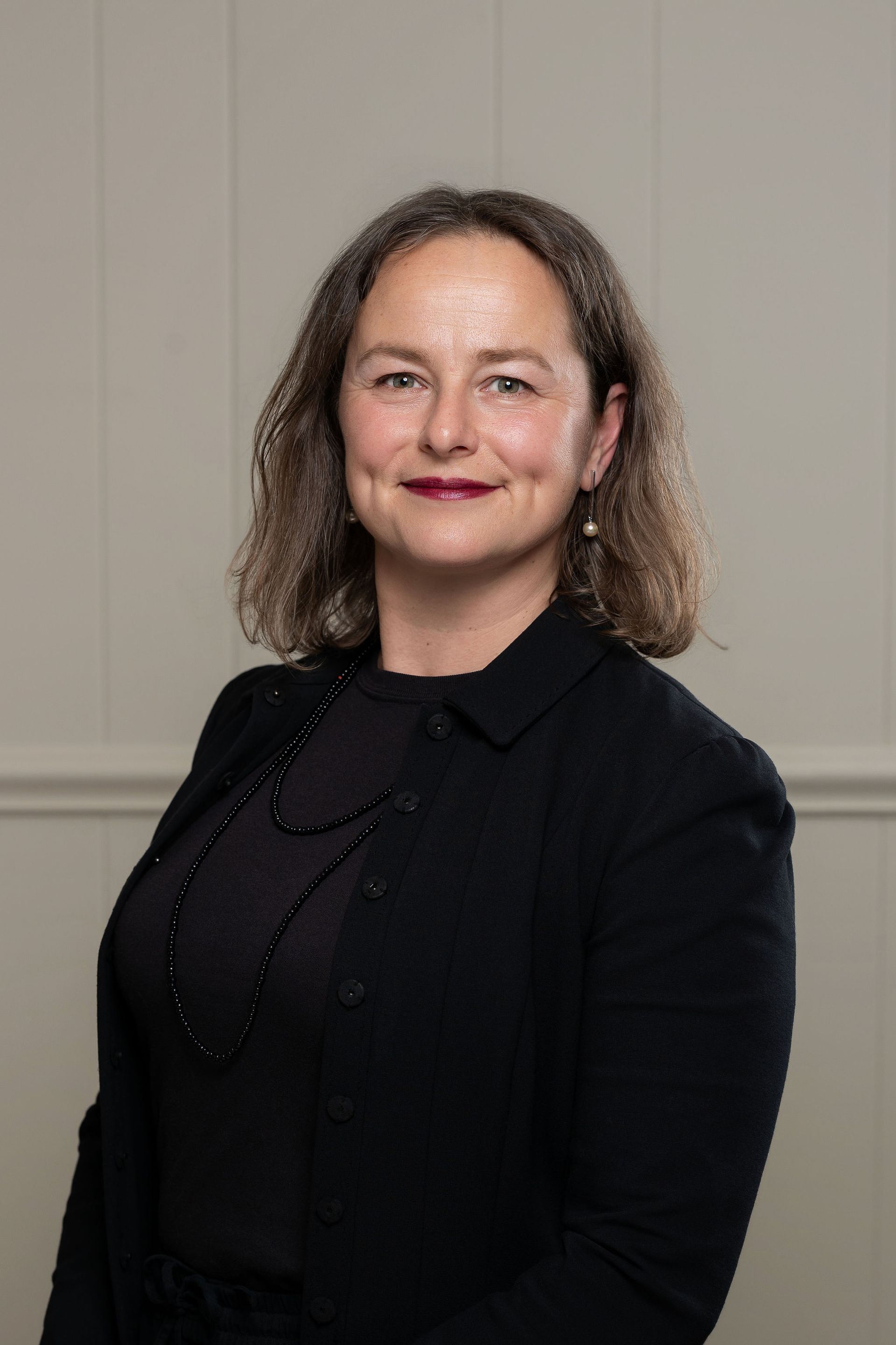 A woman in a blue dress is standing in front of three flags.