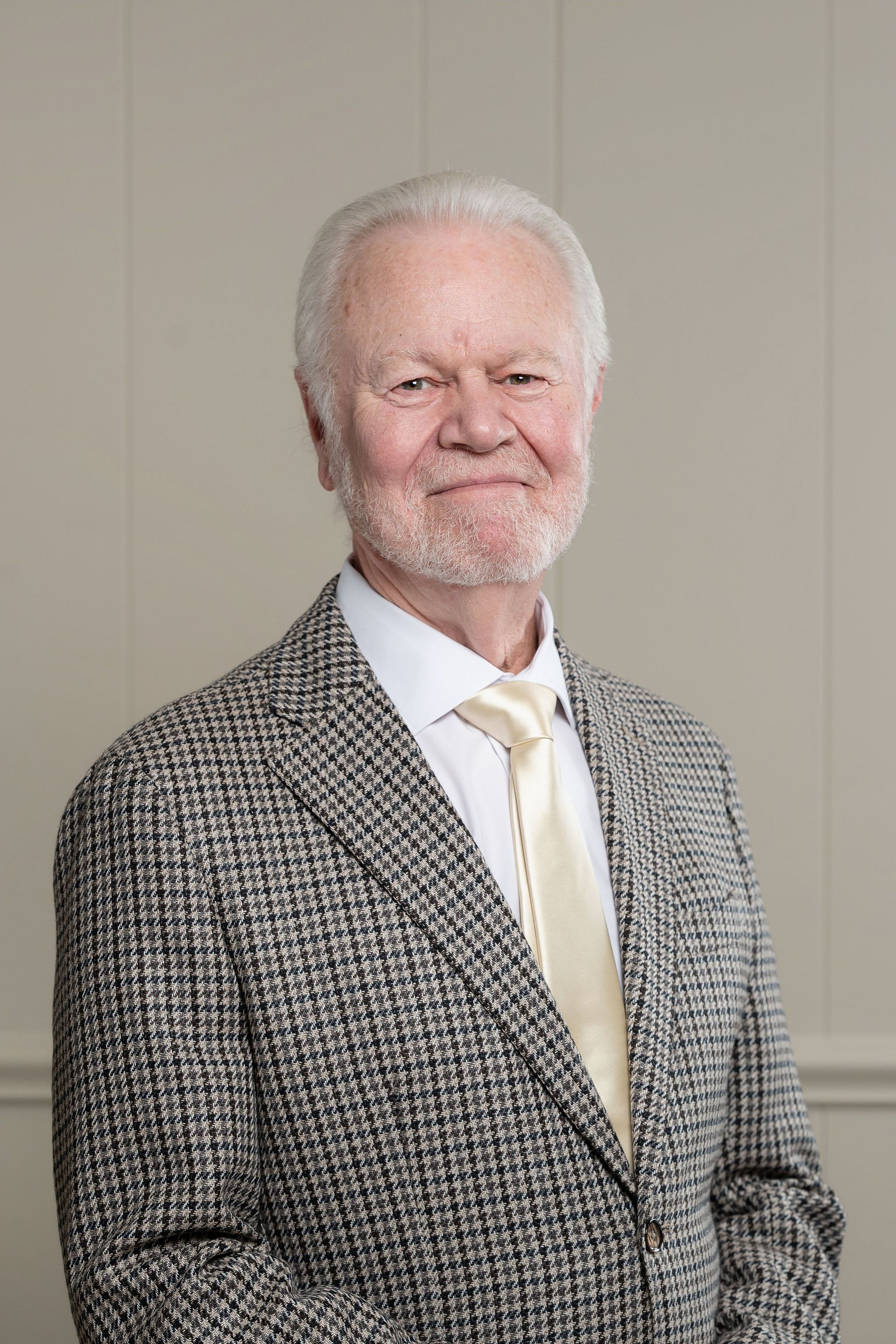 A man in a red shirt is standing in front of three flags.
