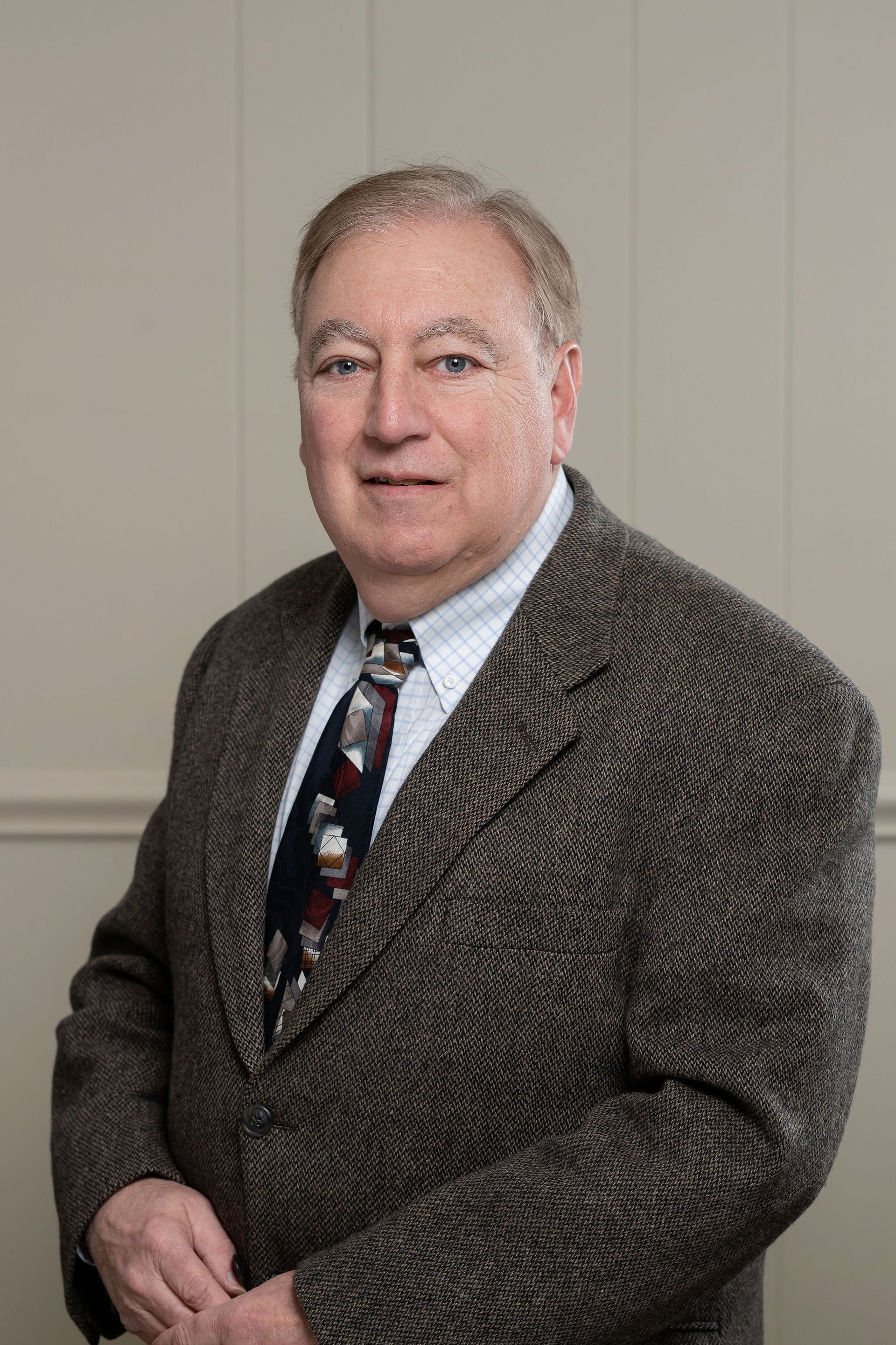 A man in a suit and tie is standing in front of flags.
