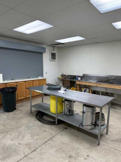 A kitchen with a large stainless steel table and sinks.