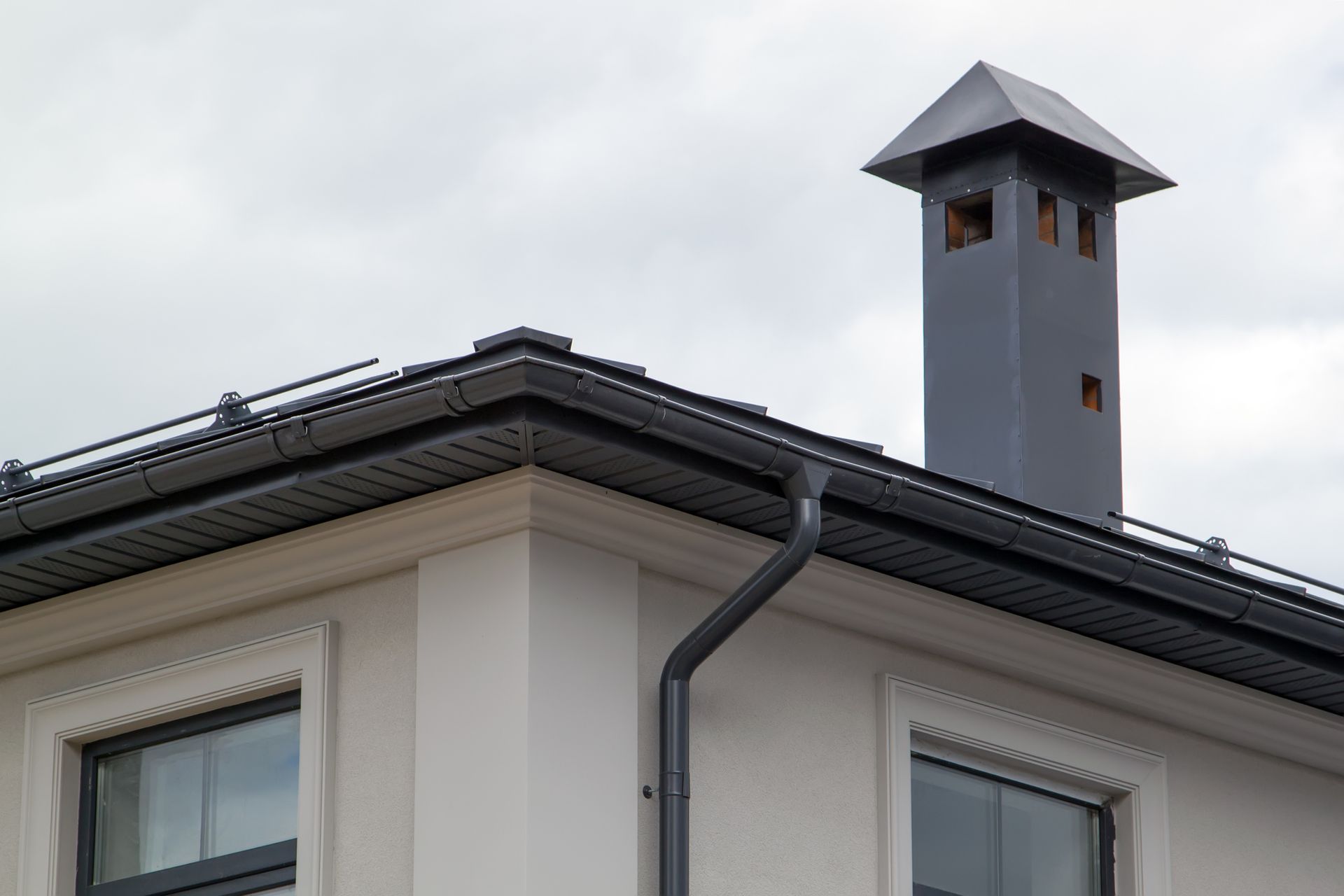 A house with a chimney on the roof and a gutter.