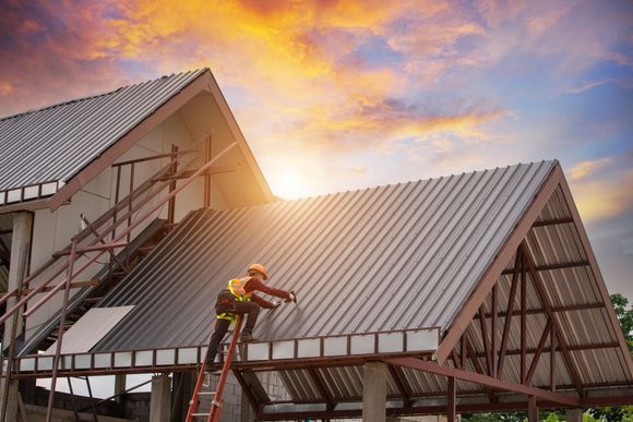 A construction worker is working on the roof of a building.