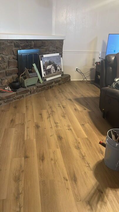 Living room with wood flooring, stone fireplace, and artwork on the hearth.