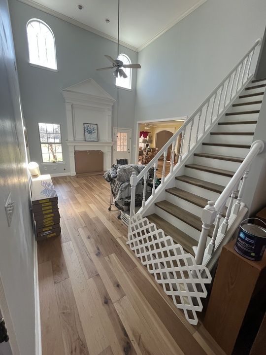 Spacious home interior with wooden floors, staircase, high ceilings, and a fireplace. Light blue walls.