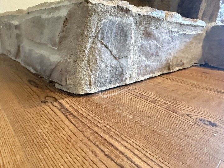 Rock-like material sits atop hardwood flooring. Brown, textured stones with light gray accents.