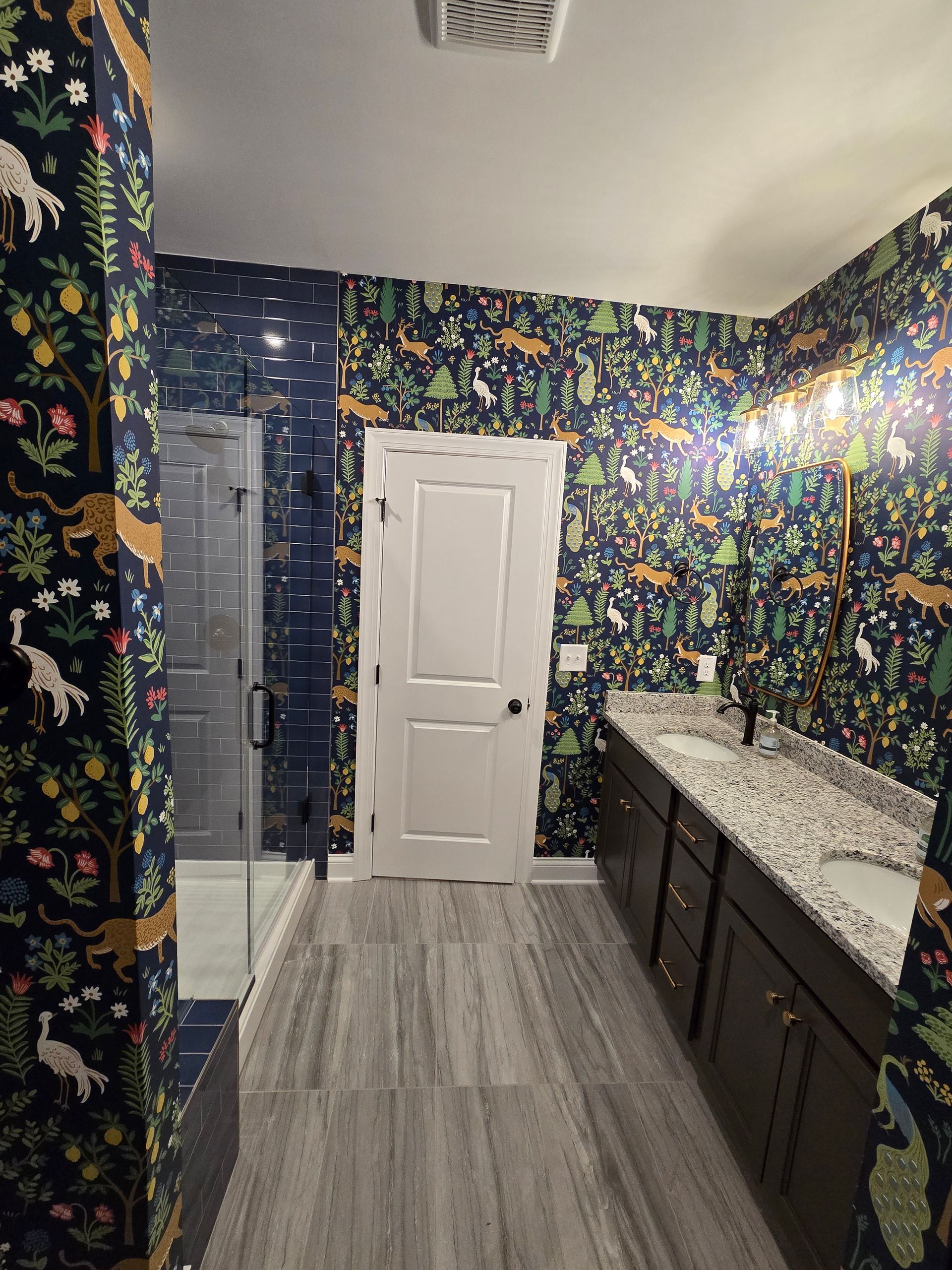 Bathroom with dark animal print wallpaper, wood cabinets, and gray tiled floor.