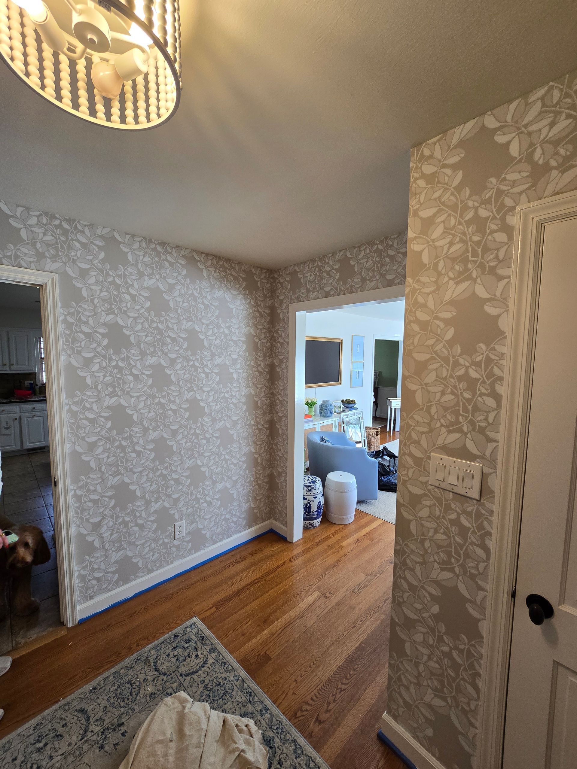 Hallway with floral wallpaper, wooden floor, open doorways to rooms.