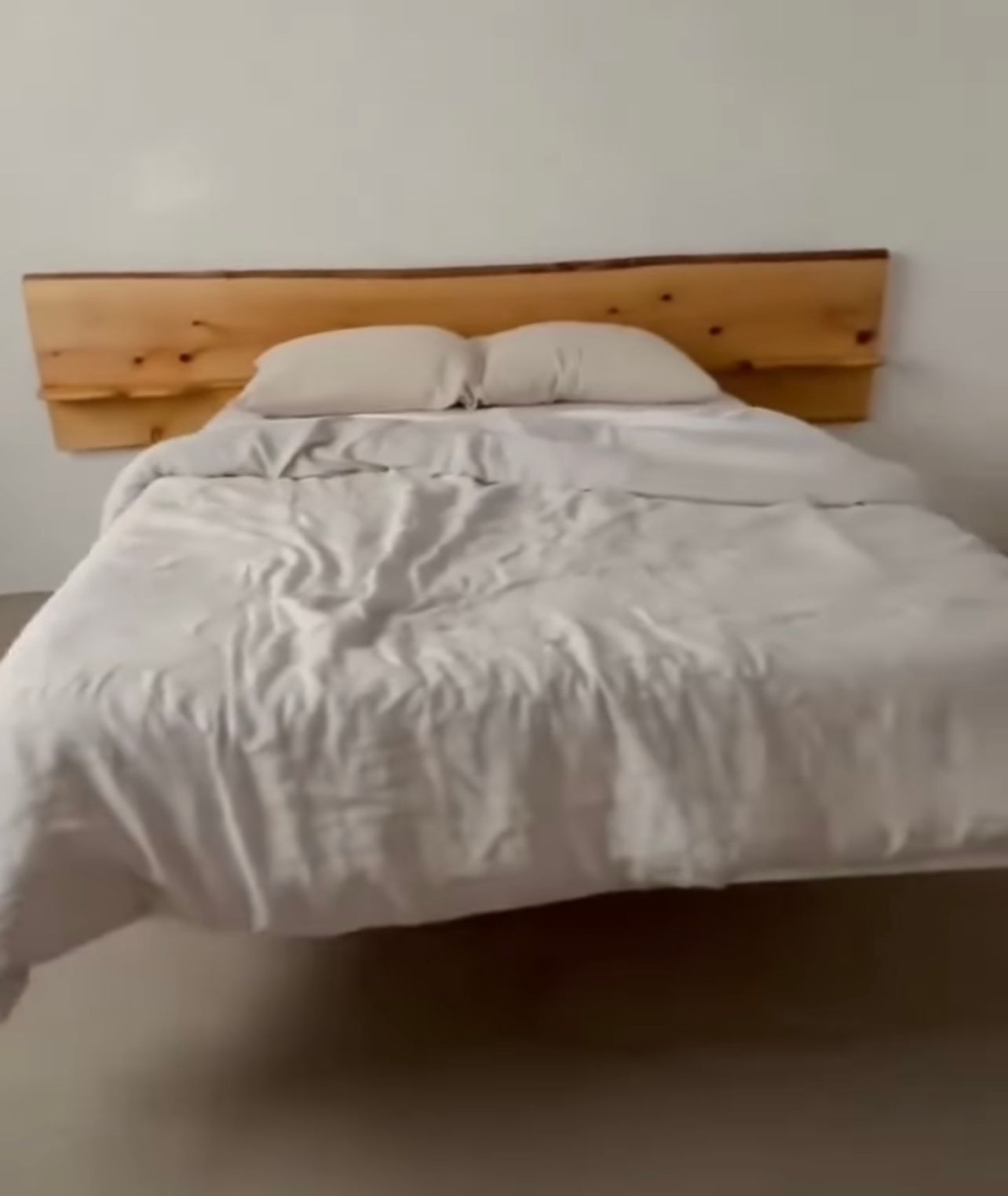 A bed with white sheets and a wooden headboard