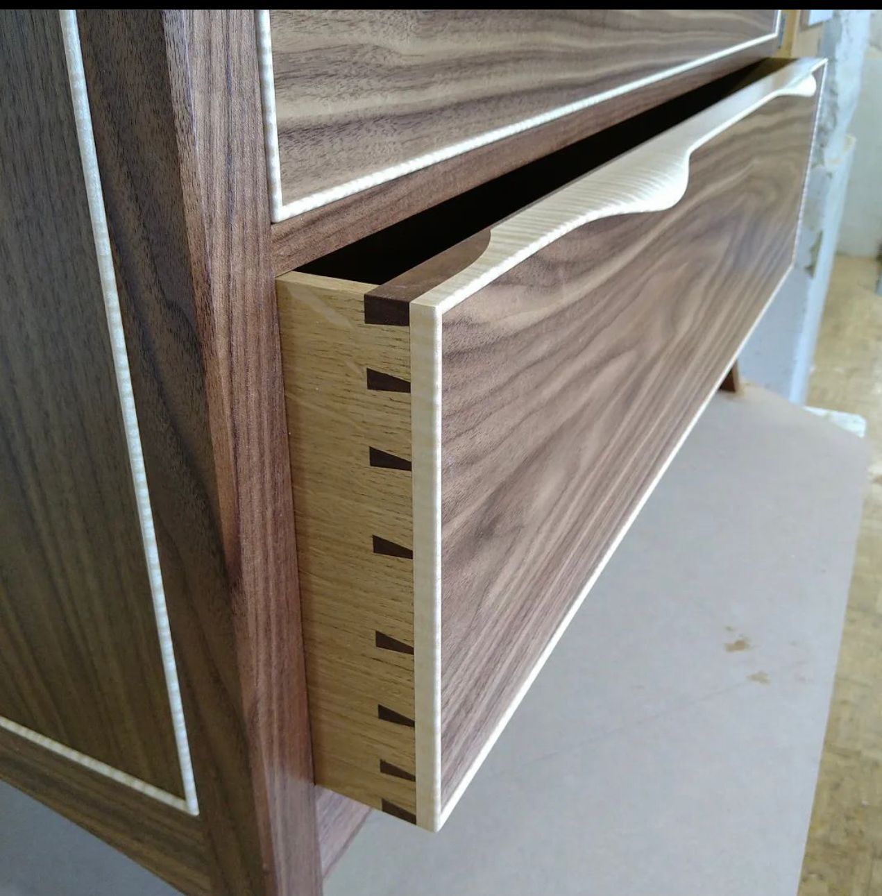 A close up of a wooden drawer with a white handle