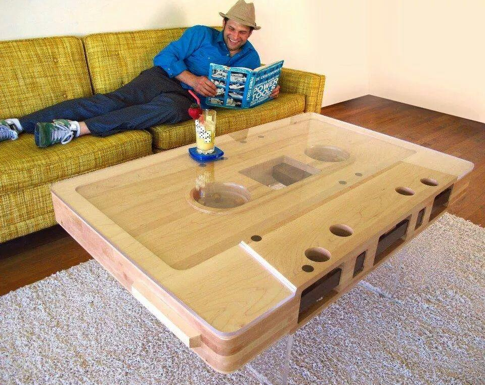 A man laying on a couch reading a book on a cassette tape table