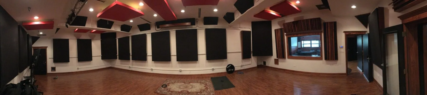 A large empty room with a wooden floor and a lot of acoustic panels on the ceiling.