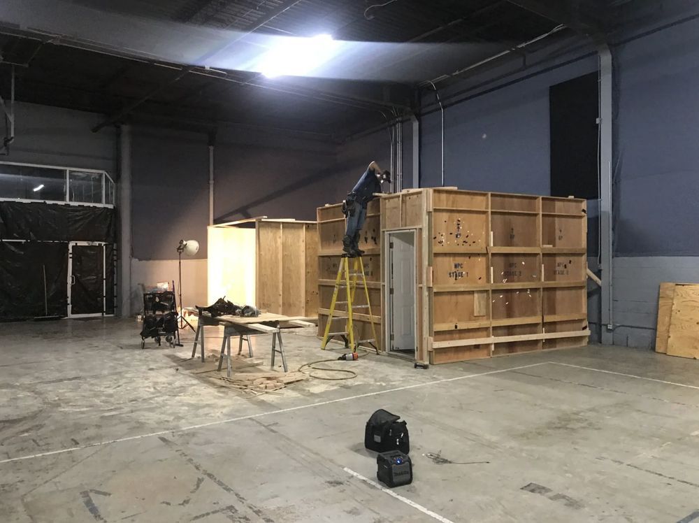 A man is standing on a ladder in a warehouse.