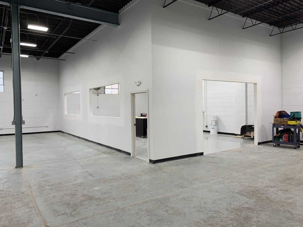 A large empty warehouse with white walls and a concrete floor.