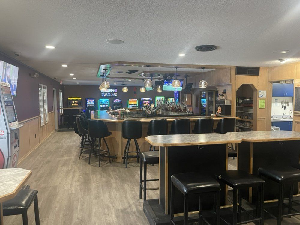 A large room with tables and chairs and a bar.