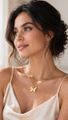 A person with dark hair styled in an updo wears a gold butterfly pendant necklace and a light-colored camisole top.