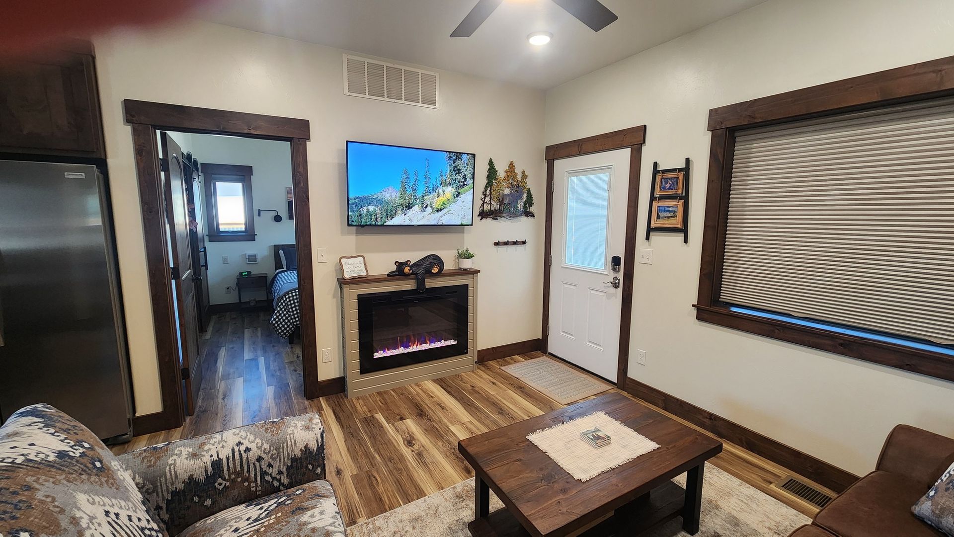 Cozy living room with fireplace, TV, wood trim, and a view into the hall.