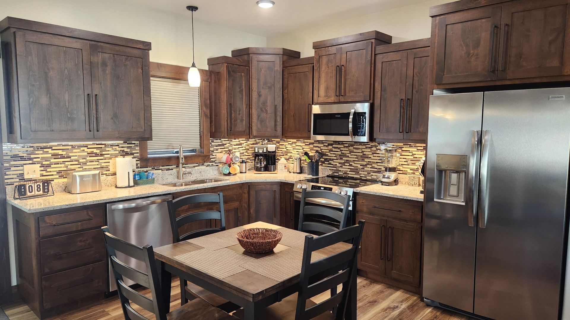 Kitchen with dark wood cabinets, stainless steel appliances, and a small dining table.
