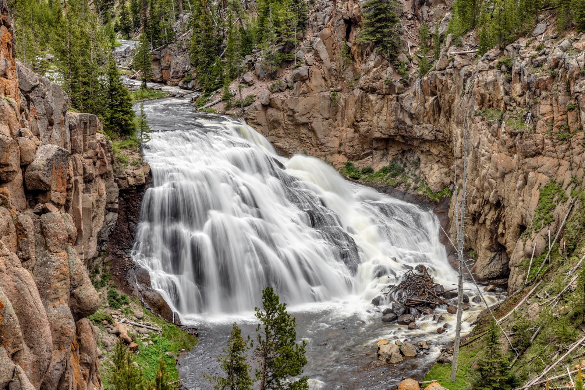 Waterfall cascading over layered rock formations in a canyon.