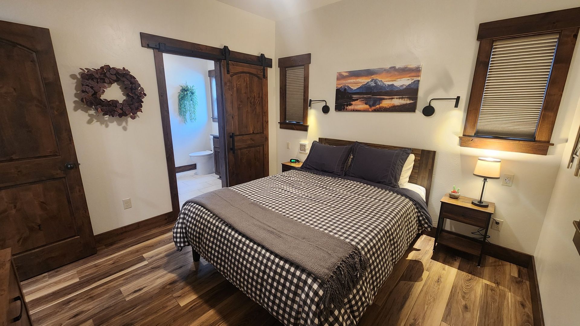 Bedroom with a bed, bathroom door, and artwork on the wall.