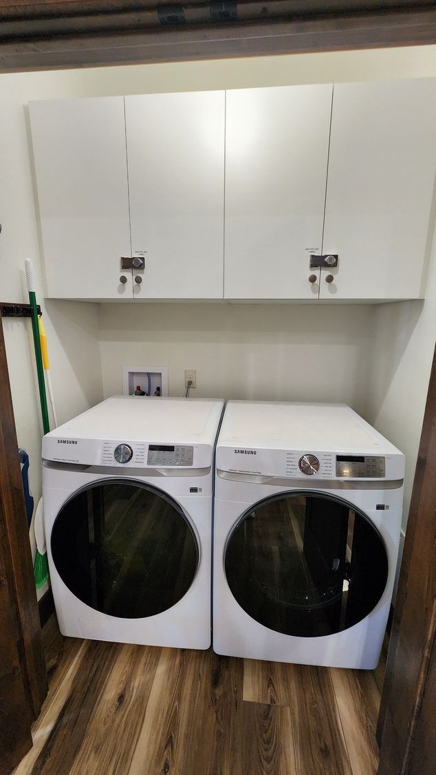 White washer and dryer below two white cabinets in a laundry room.