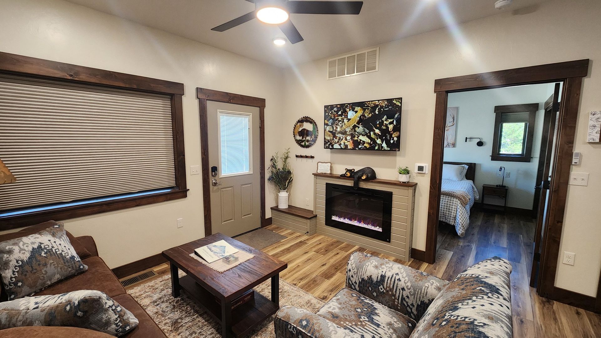 Cozy living room with fireplace, TV, and doorway to bedroom. Brown and neutral colors.