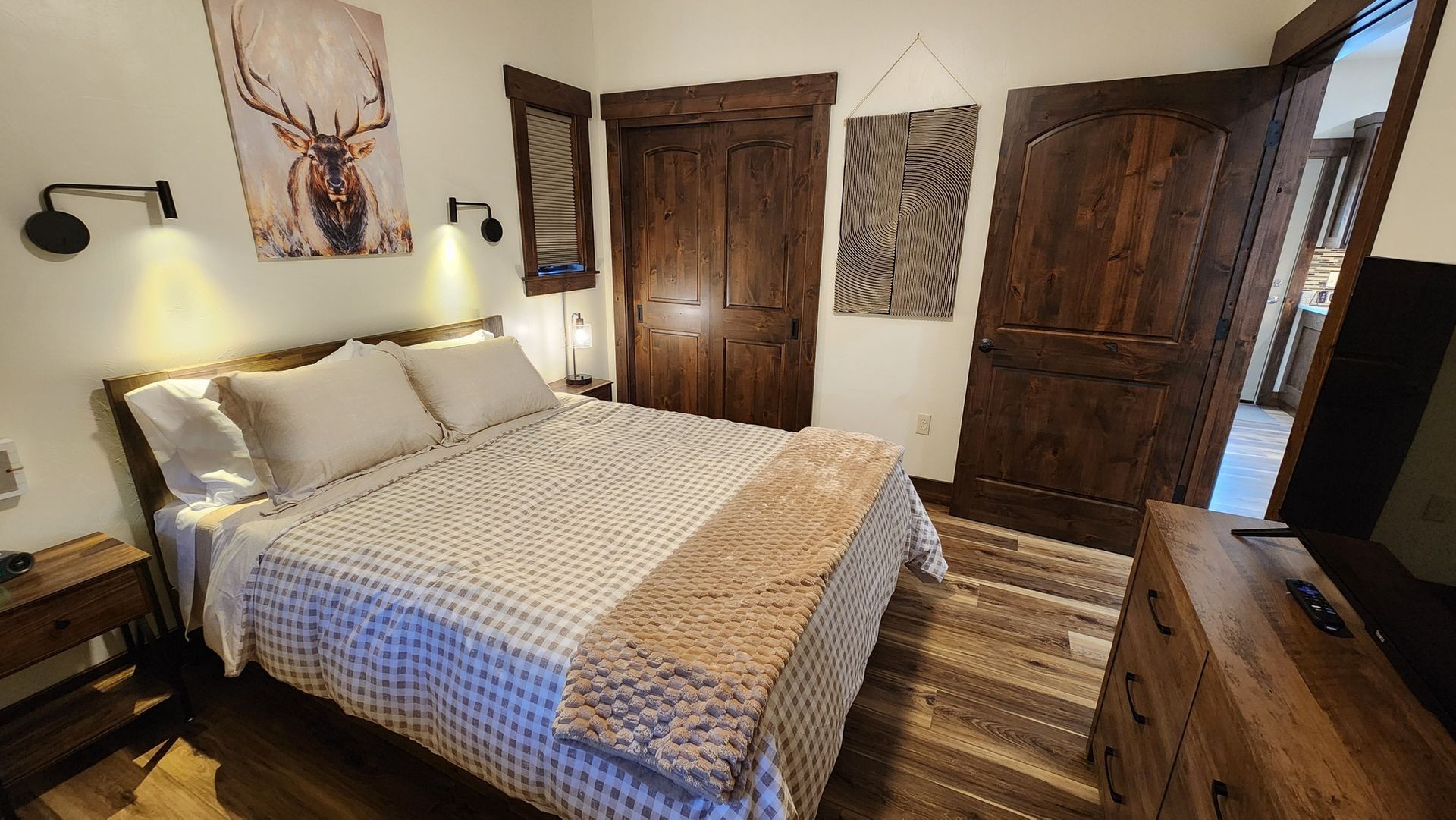 Bedroom with rustic wood furniture, bed, and artwork; earth tones, cozy lighting.