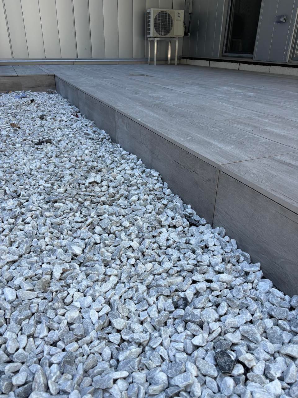 Un tas de gravier est posé sur le sol à côté d'une allée en béton.