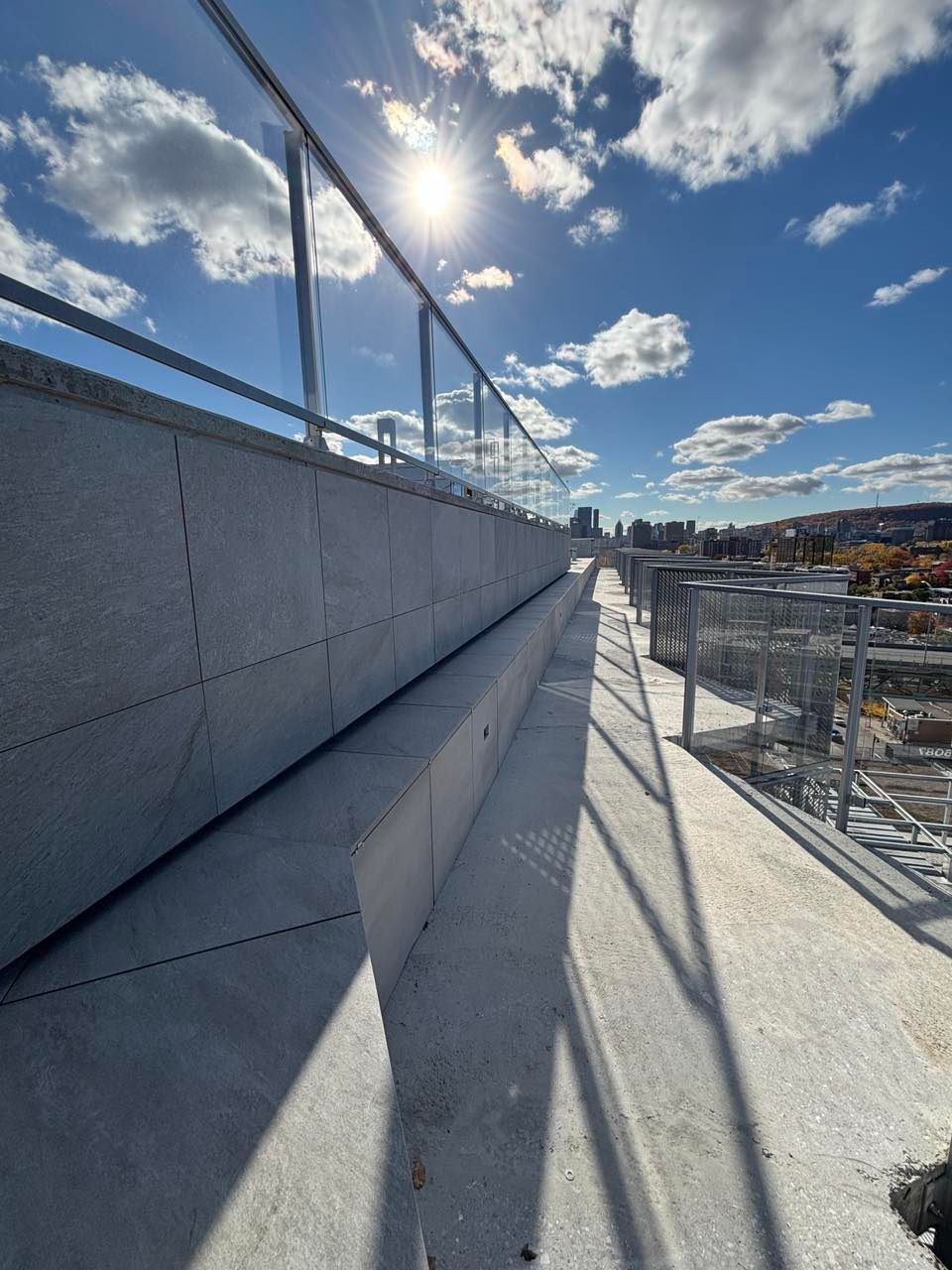 Une vue d'une ville depuis un balcon avec le soleil qui brille à travers les nuages