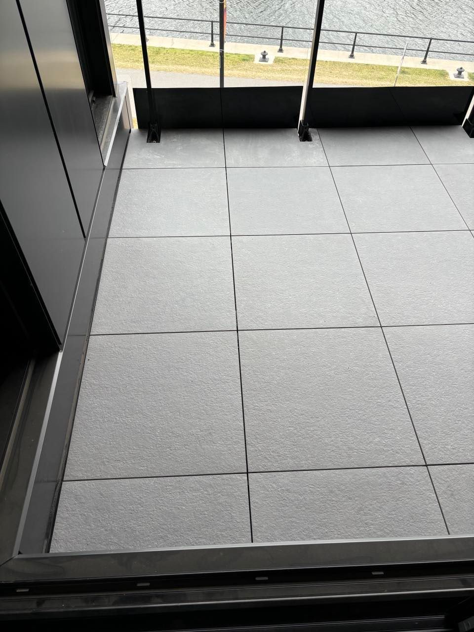 Un balcon avec carrelage au sol et vue sur l'eau.