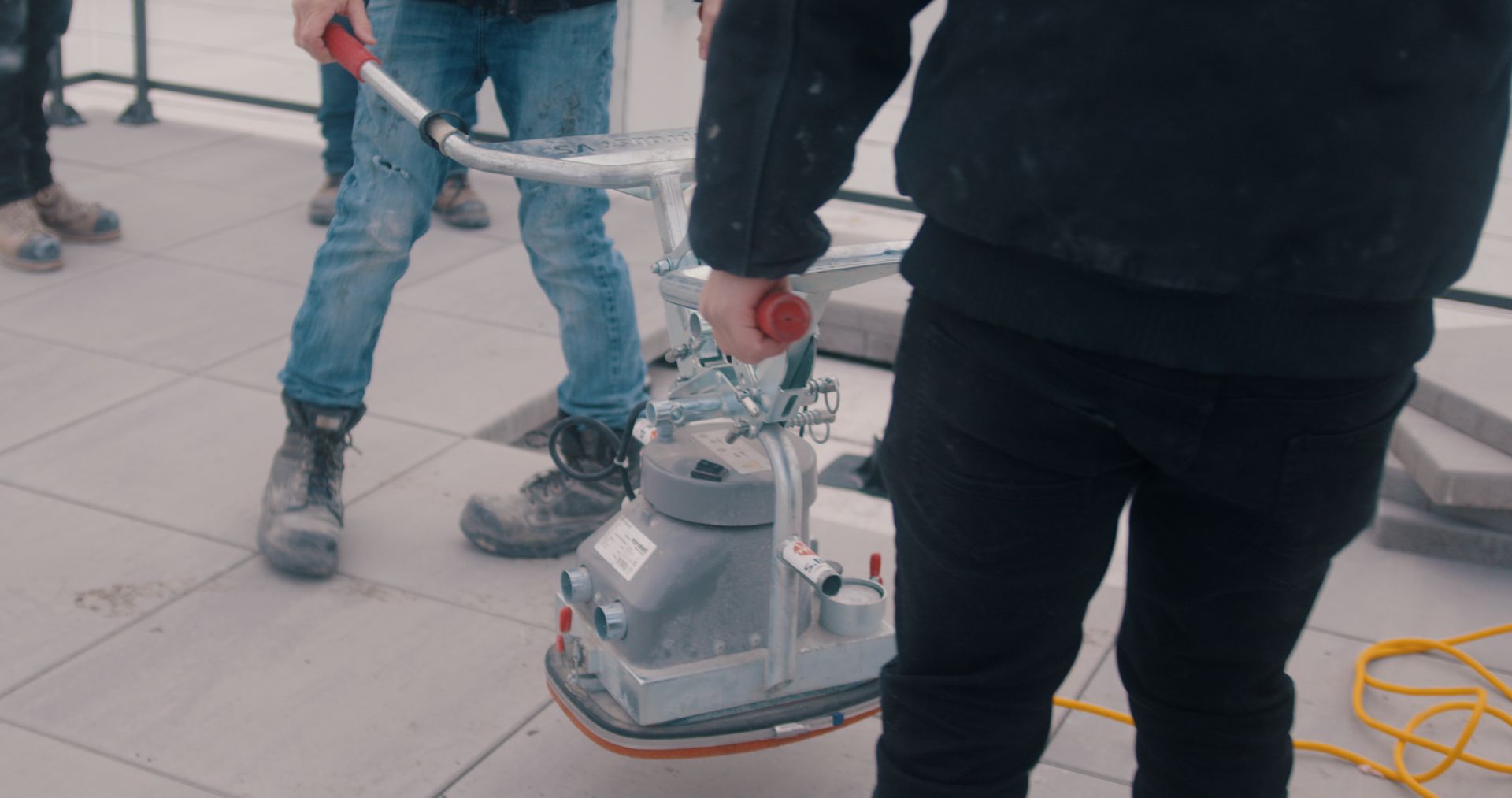 Un homme utilise un aspirateur pour nettoyer un sol carrelé.