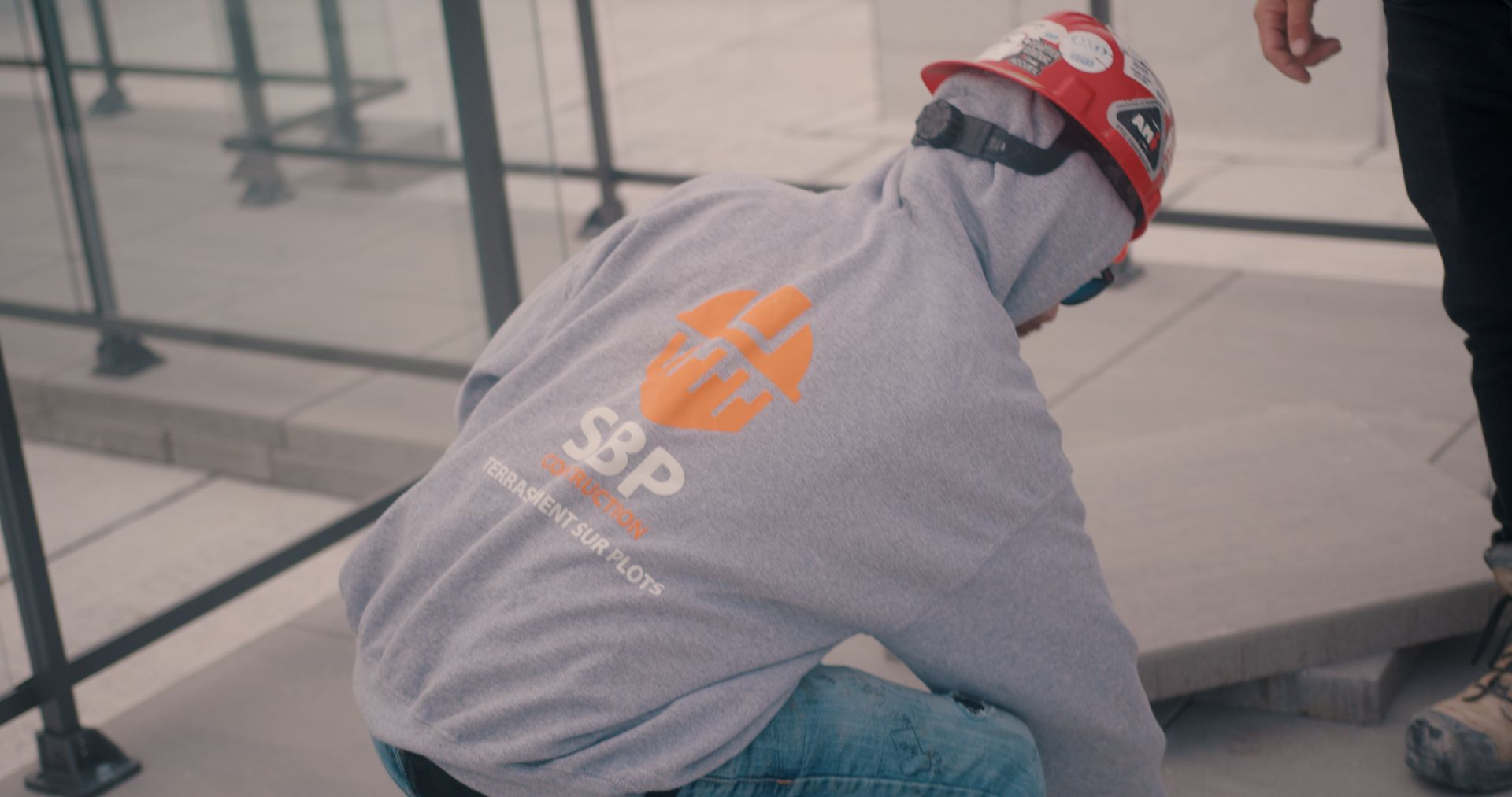 Un homme portant un casque et un sweat à capuche est à genoux sur le sol.