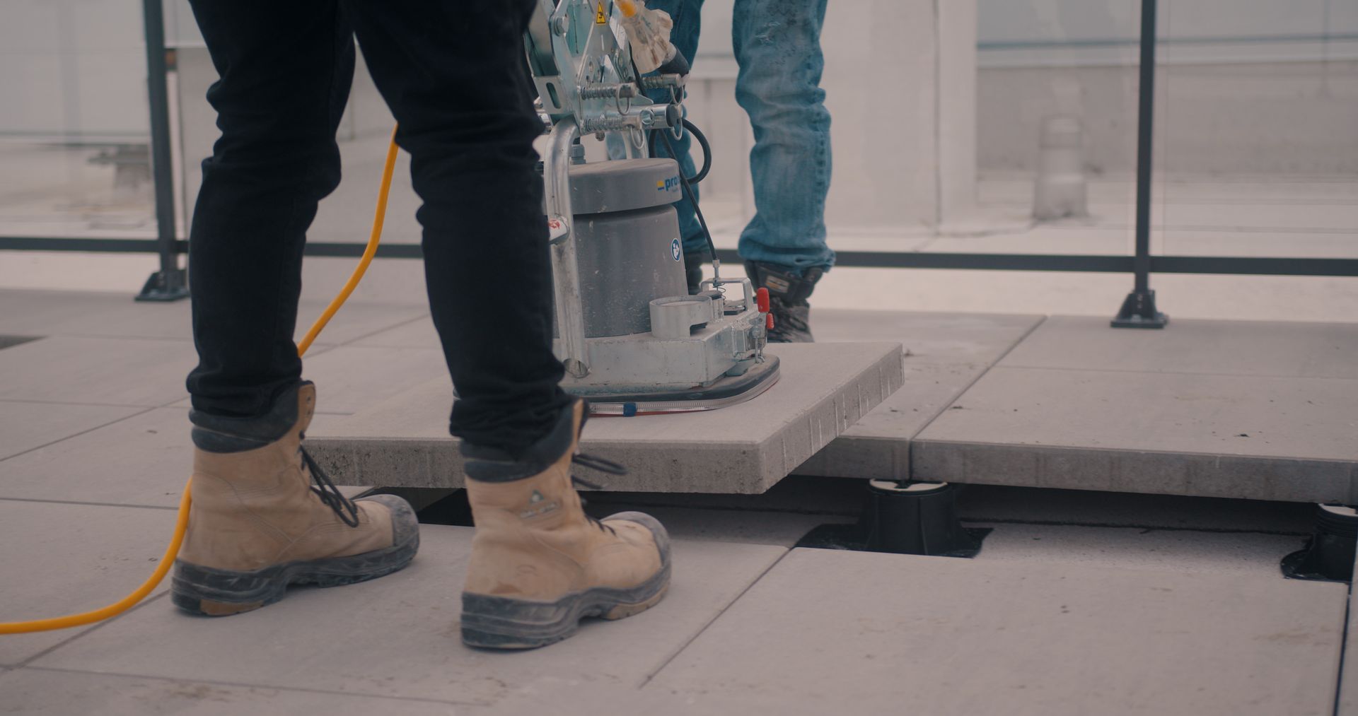 Un homme se tient debout à côté d'une machine sur un sol en béton.