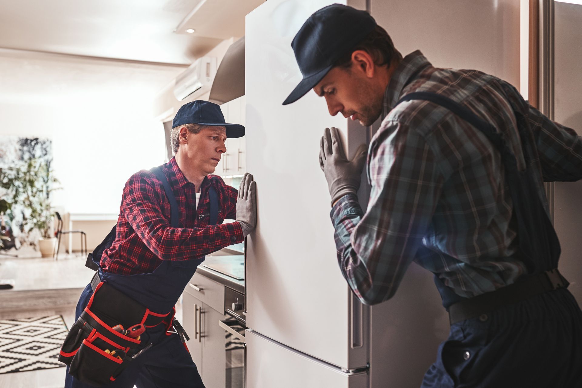 Two men are installing a refrigerator in a kitchen.