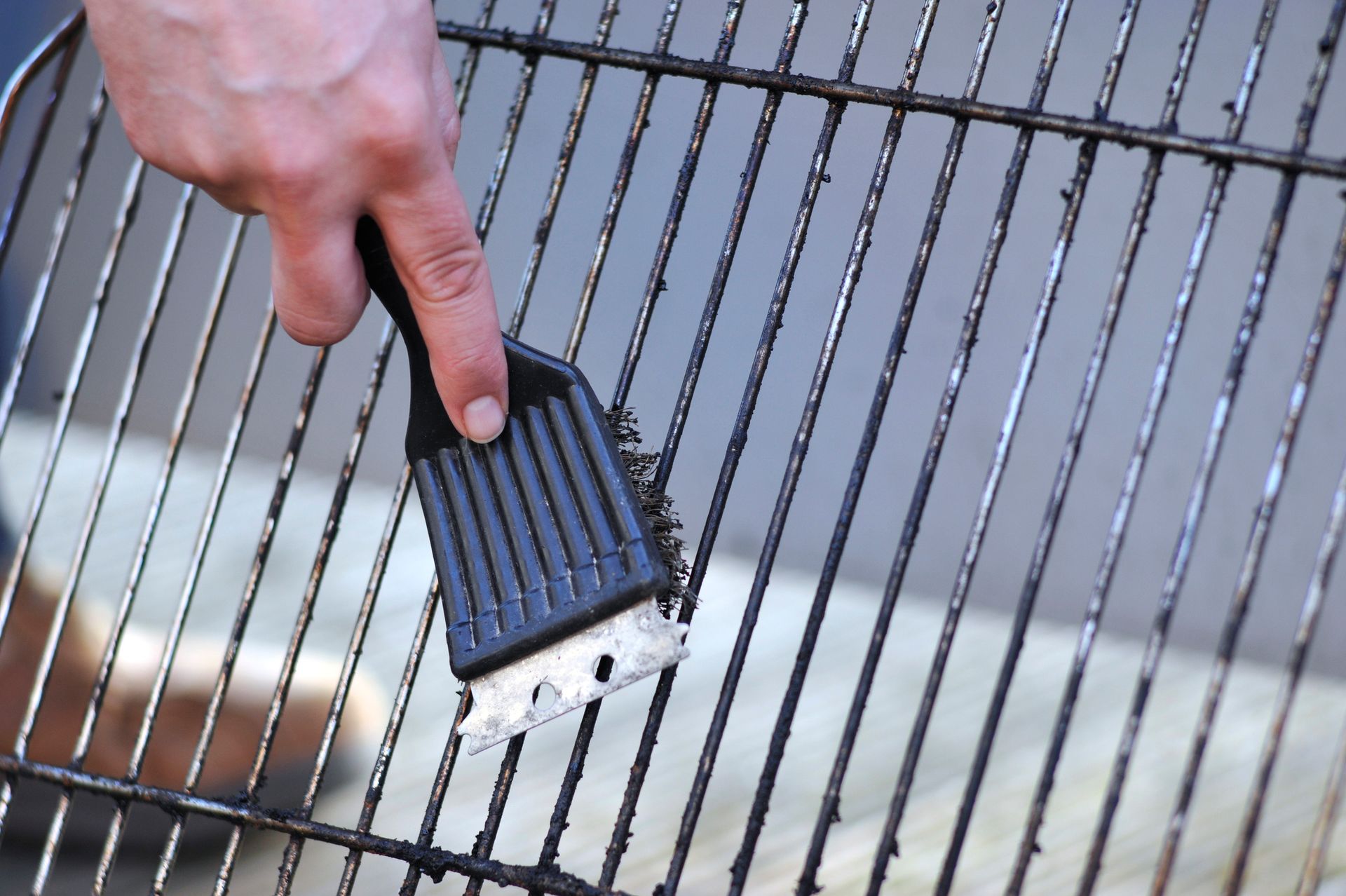 A person is cleaning a grill with a brush.