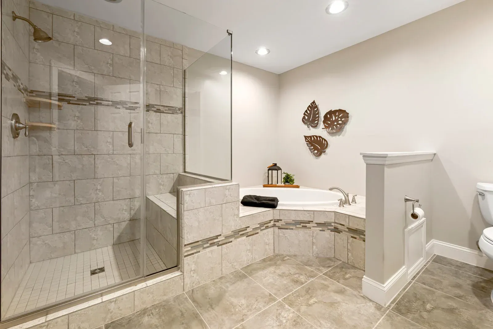Spacious bathroom with glass shower, built-in tub, beige tiles, and decorative wall art.