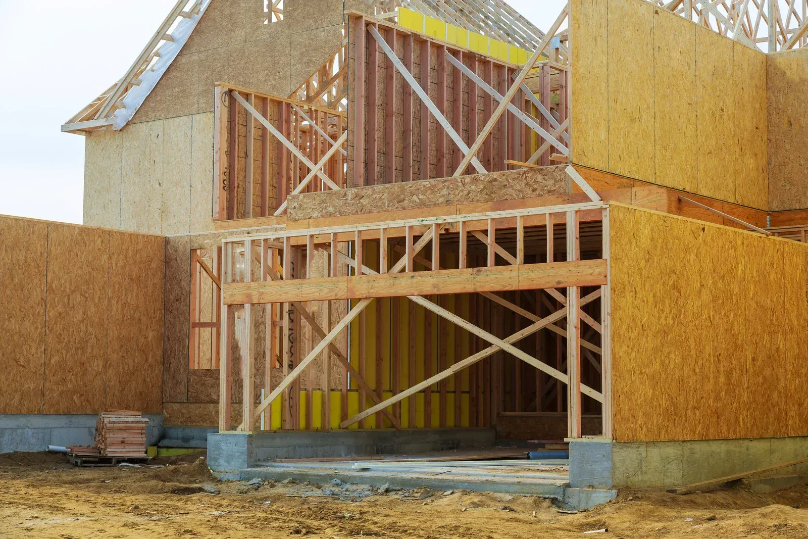 Wooden frame of a house under construction; garage opening visible.