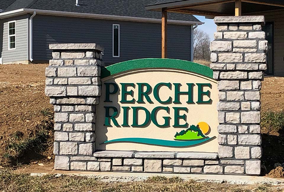 A sign for perche ridge is in front of a house